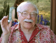 Irving Dayton, an older man with glasses and white hair looks at the camera. 